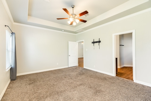 unfurnished bedroom with ornamental molding, carpet flooring, ceiling fan, and a raised ceiling