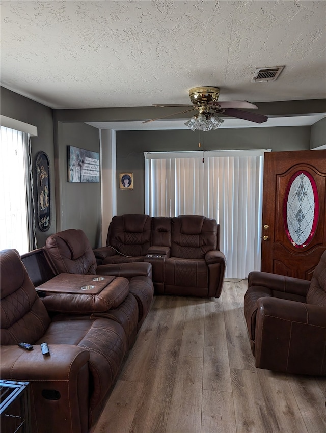 living room featuring ceiling fan, wood-type flooring, and a textured ceiling