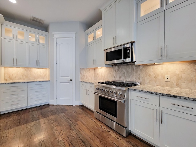 kitchen featuring stainless steel appliances, light stone countertops, white cabinets, and decorative backsplash