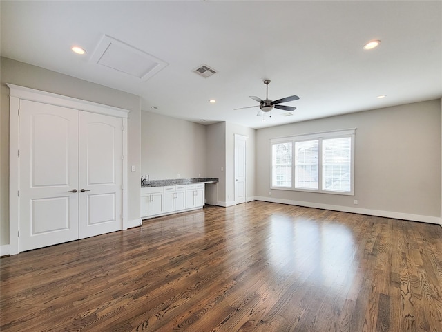 unfurnished living room featuring dark wood-type flooring and ceiling fan