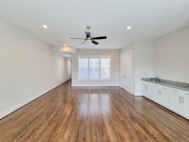 unfurnished living room featuring sink, dark wood-type flooring, and ceiling fan