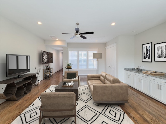 living room featuring wood-type flooring, sink, and ceiling fan