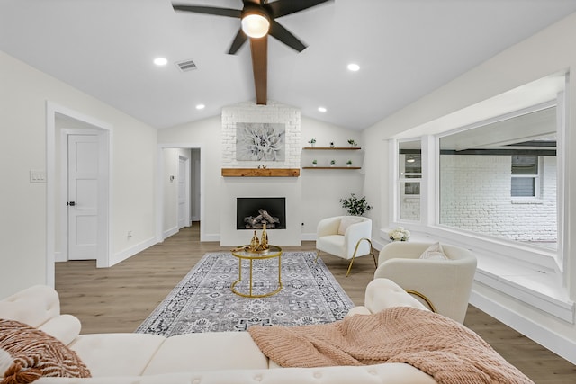 living room featuring lofted ceiling with beams, a fireplace, hardwood / wood-style flooring, and ceiling fan