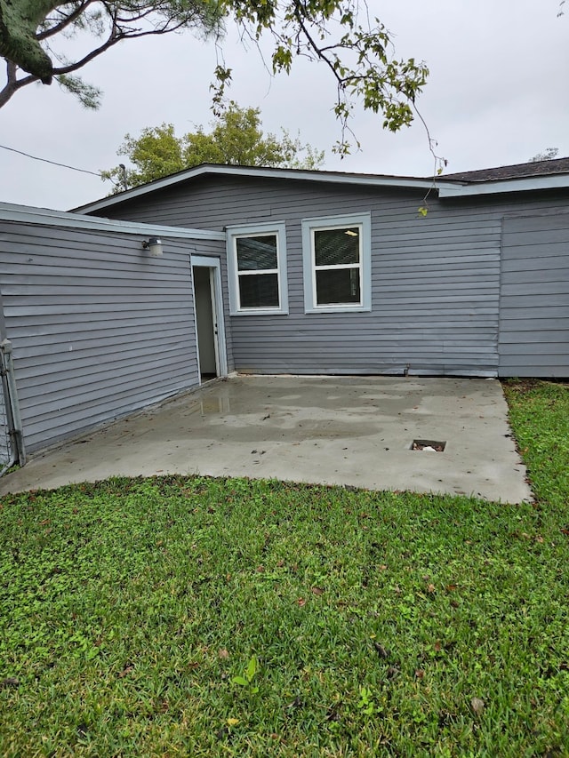 rear view of house featuring a lawn and a patio