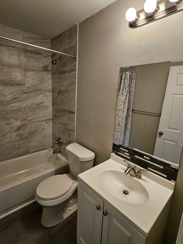 full bathroom featuring vanity, a textured ceiling, tiled shower / bath combo, hardwood / wood-style floors, and toilet