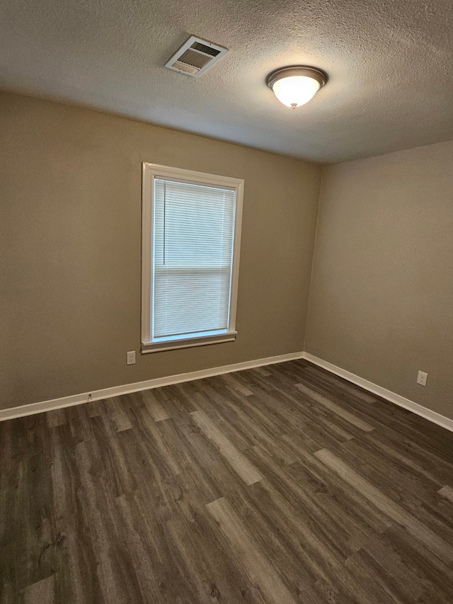 unfurnished room with dark hardwood / wood-style flooring and a textured ceiling