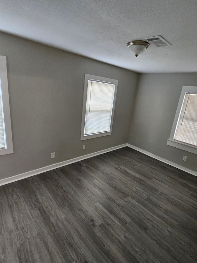 unfurnished room with dark wood-type flooring and a textured ceiling