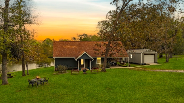 ranch-style home featuring an outdoor structure, a yard, a water view, and a garage