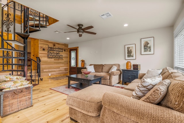 living room with light wood-type flooring, wooden walls, and ceiling fan