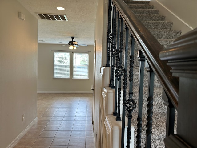 staircase with ceiling fan, tile patterned flooring, and a textured ceiling