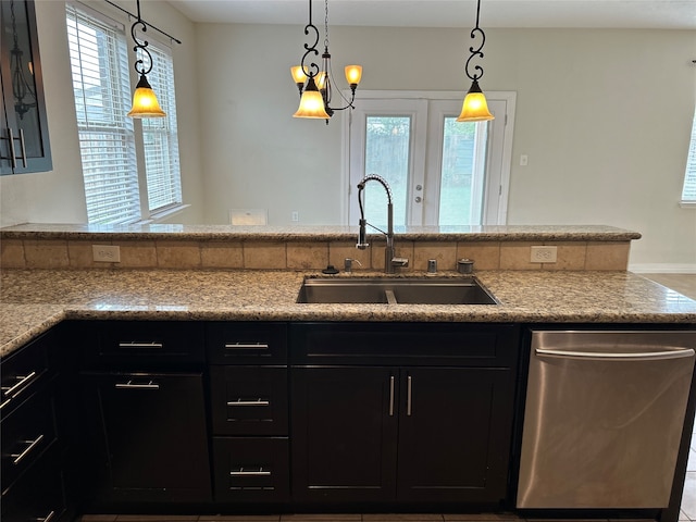 kitchen featuring a wealth of natural light, sink, hanging light fixtures, and stainless steel dishwasher