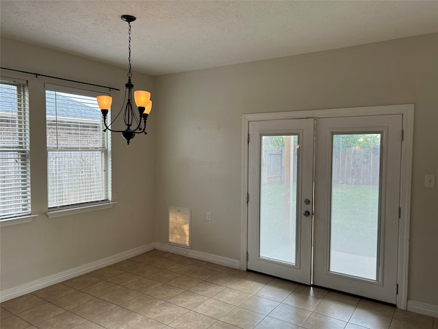 entryway featuring a chandelier, light tile patterned floors, and a textured ceiling