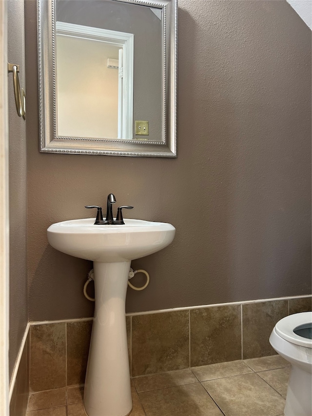 bathroom with toilet, tile patterned floors, and sink