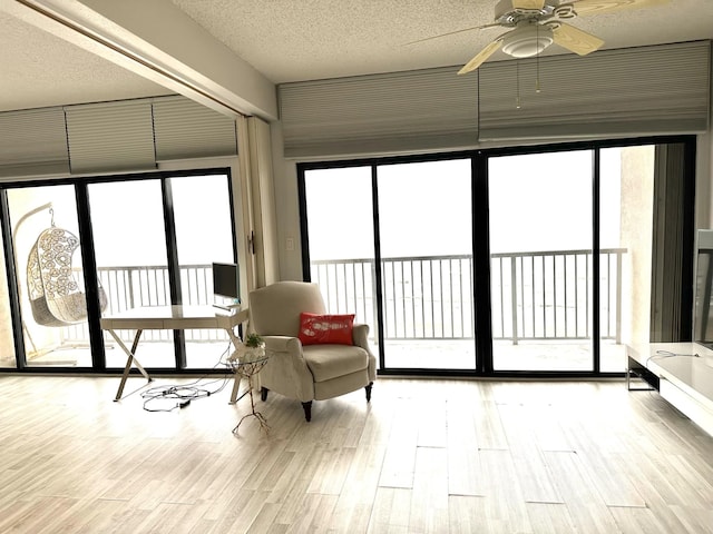 interior space with ceiling fan, floor to ceiling windows, a textured ceiling, and light hardwood / wood-style floors