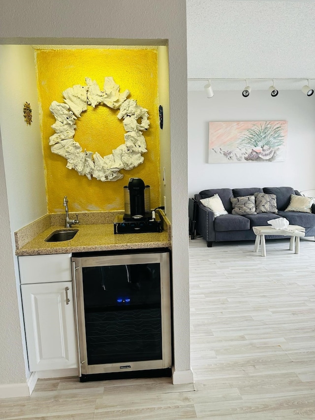 bar with white cabinets, light hardwood / wood-style floors, sink, and wine cooler