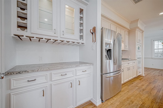 kitchen with light stone countertops, white appliances, crown molding, light hardwood / wood-style floors, and white cabinetry