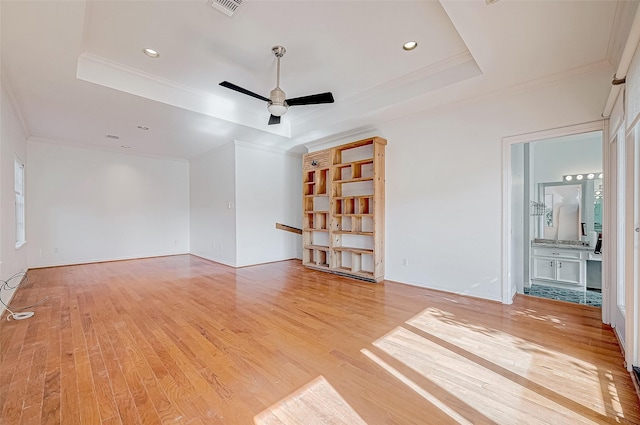 unfurnished living room featuring light hardwood / wood-style floors, ceiling fan, and a tray ceiling