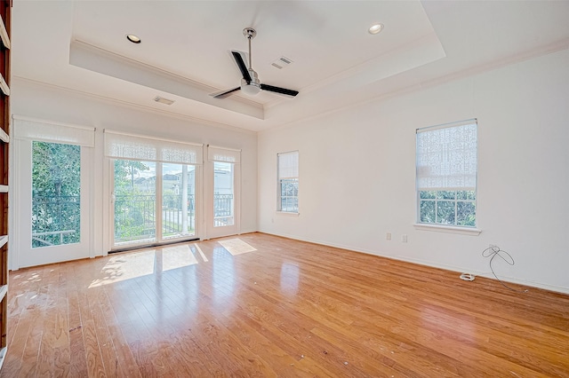 unfurnished room featuring a tray ceiling, ceiling fan, light hardwood / wood-style flooring, and crown molding