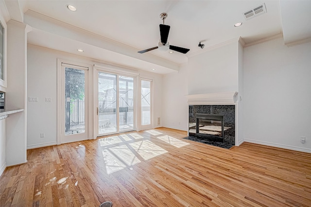 unfurnished living room with ceiling fan, light wood-type flooring, crown molding, and a tiled fireplace