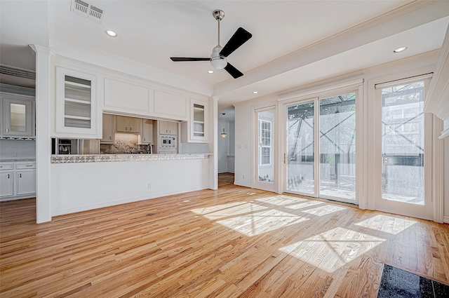 unfurnished living room featuring crown molding, ceiling fan, a healthy amount of sunlight, and light wood-type flooring