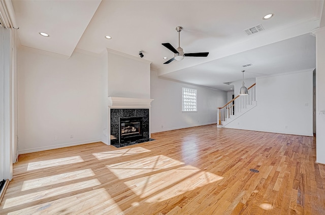 unfurnished living room featuring ceiling fan, light hardwood / wood-style flooring, a high end fireplace, and ornamental molding