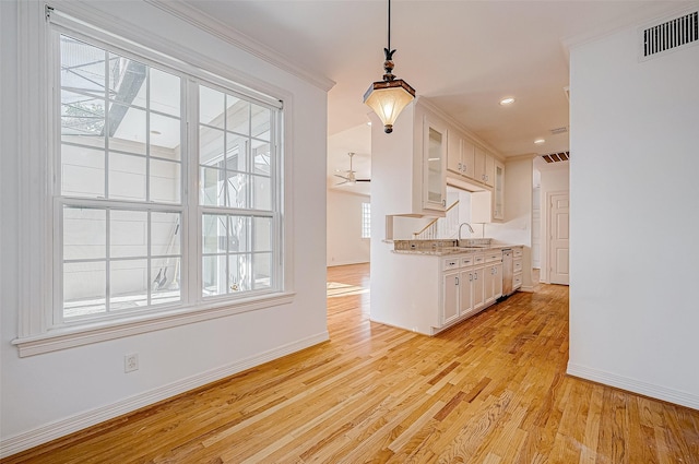 kitchen featuring white cabinetry, a wealth of natural light, light hardwood / wood-style flooring, and pendant lighting