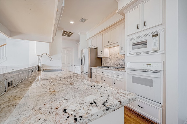 kitchen with sink, light wood-type flooring, appliances with stainless steel finishes, light stone counters, and white cabinetry