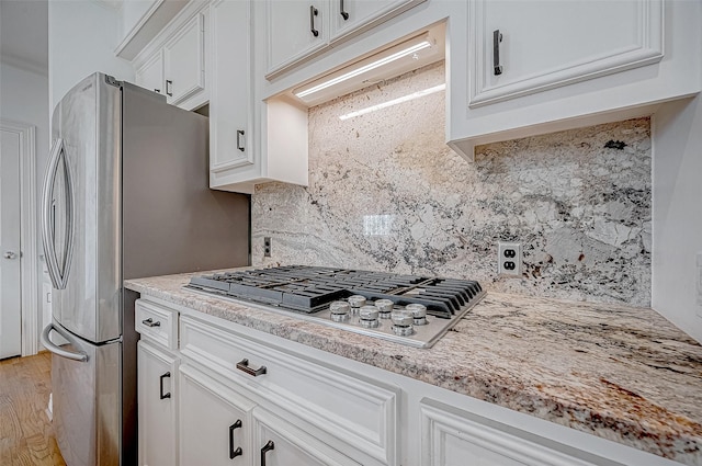 5031 Nolda St, Houston, TX 77007 - kitchen featuring stainless steel gas stovetop, under cabinet range hood, white cabinets, and tasteful backsplash