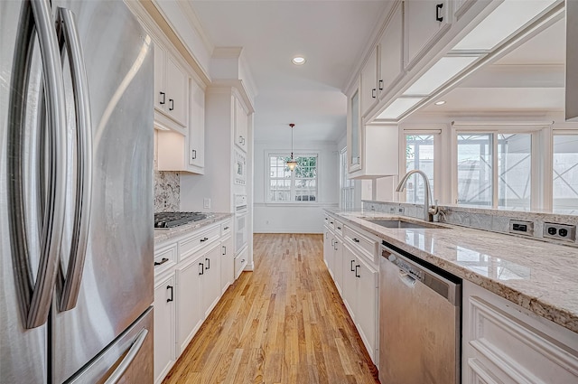 kitchen featuring white cabinets, sink, hanging light fixtures, light hardwood / wood-style flooring, and appliances with stainless steel finishes