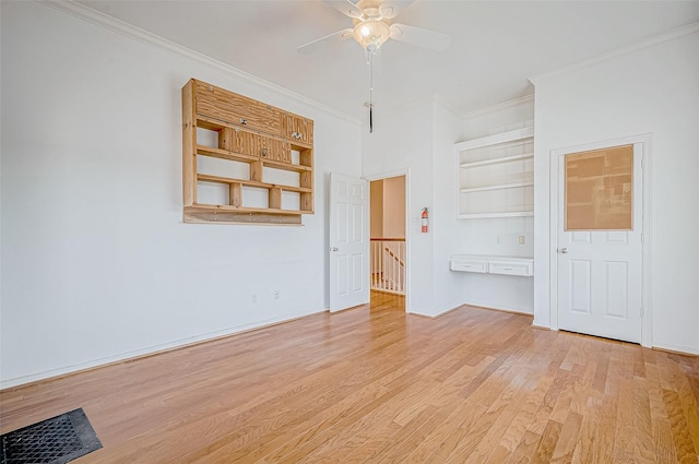 empty room featuring ceiling fan, ornamental molding, built in shelves, and light hardwood / wood-style flooring