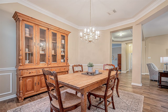 dining space with dark hardwood / wood-style floors, an inviting chandelier, and crown molding