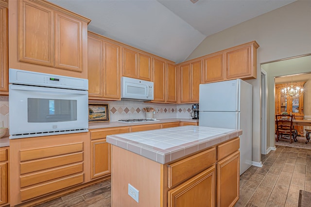 kitchen featuring tasteful backsplash, hardwood / wood-style floors, white appliances, lofted ceiling, and a center island