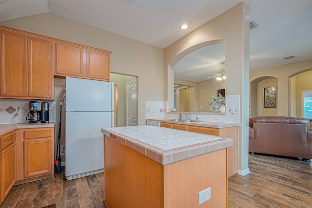 kitchen featuring white fridge, a kitchen island, backsplash, sink, and hardwood / wood-style flooring