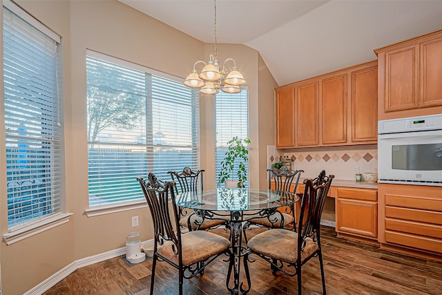 dining area featuring a wealth of natural light, lofted ceiling, a notable chandelier, and dark hardwood / wood-style flooring