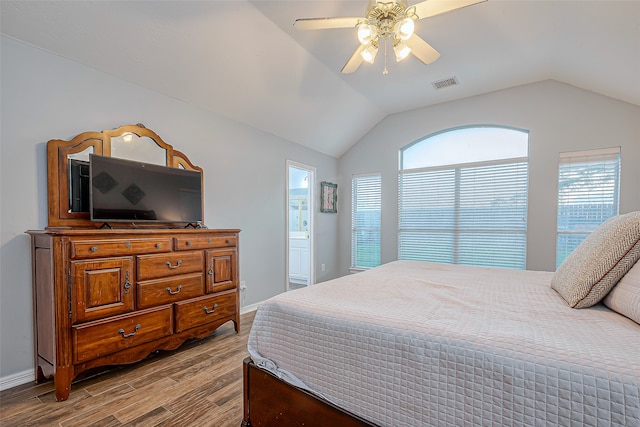 bedroom featuring multiple windows, light hardwood / wood-style flooring, ceiling fan, and ensuite bath