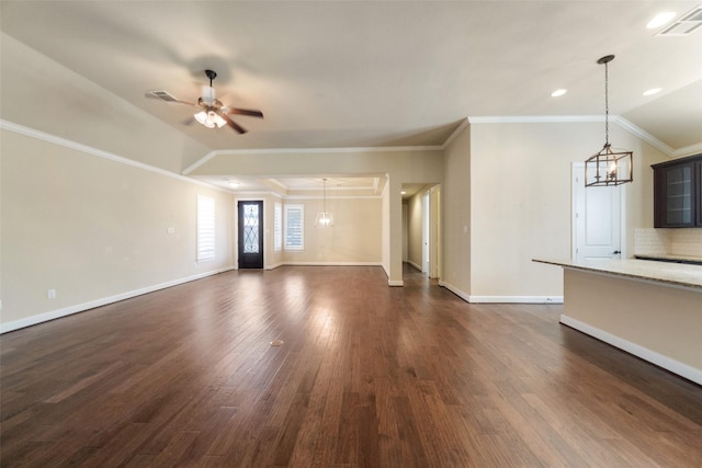 unfurnished living room with ceiling fan with notable chandelier, dark hardwood / wood-style floors, ornamental molding, and vaulted ceiling