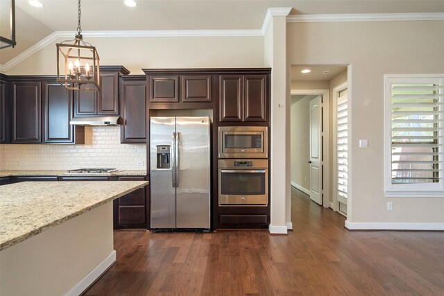 kitchen featuring light stone countertops, decorative backsplash, dark brown cabinetry, stainless steel appliances, and crown molding