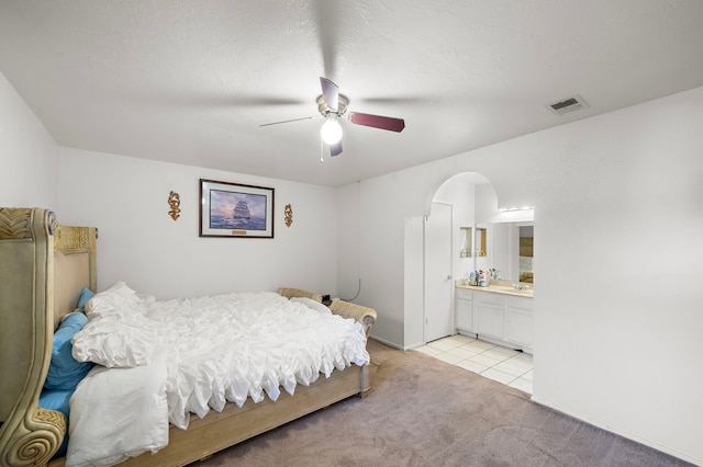 carpeted bedroom featuring ensuite bath and ceiling fan