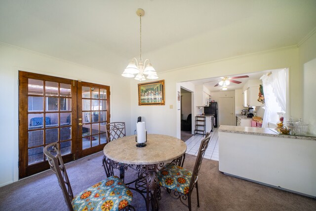 carpeted dining area with french doors and ceiling fan with notable chandelier