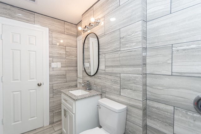 bathroom with tile walls, vanity, and toilet