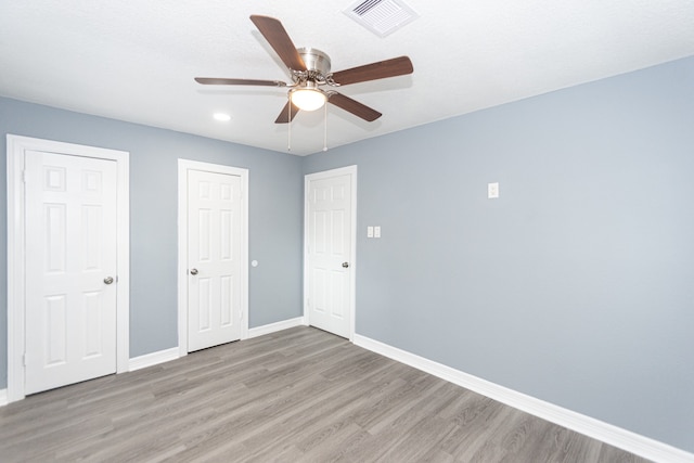 unfurnished bedroom featuring light hardwood / wood-style floors, ceiling fan, and two closets