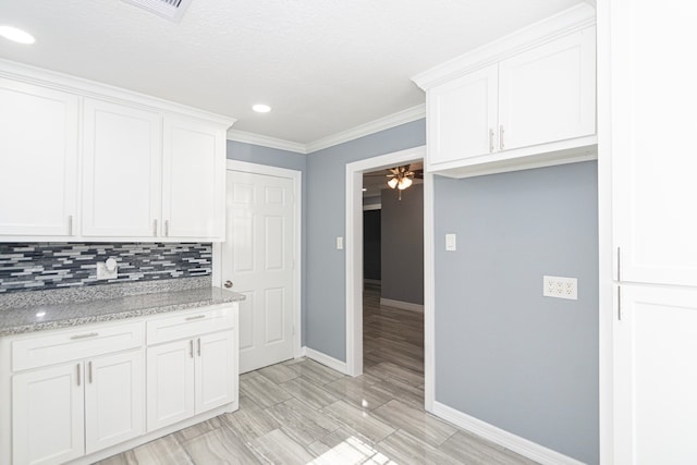 kitchen with ornamental molding, white cabinetry, light stone counters, and tasteful backsplash