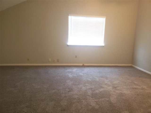 spare room featuring dark carpet and lofted ceiling