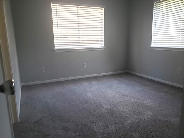 empty room featuring dark colored carpet and a healthy amount of sunlight