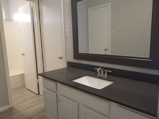 bathroom with a bath, vanity, and hardwood / wood-style flooring