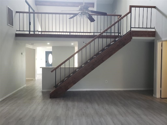 stairway with hardwood / wood-style flooring, ceiling fan, and a high ceiling