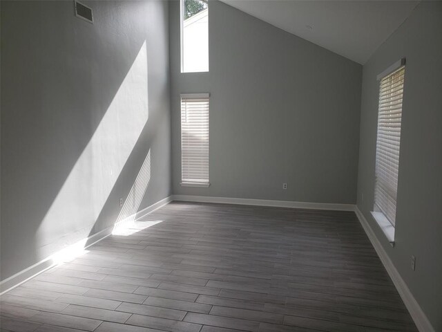 unfurnished room with hardwood / wood-style flooring and high vaulted ceiling