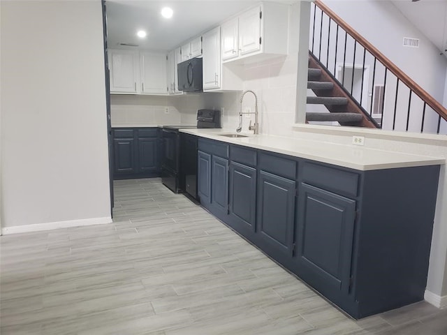 kitchen featuring white cabinetry, sink, light hardwood / wood-style flooring, backsplash, and black appliances