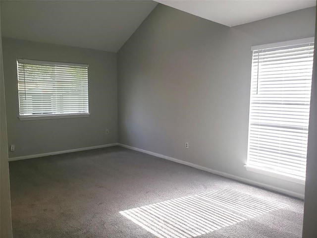 carpeted empty room featuring plenty of natural light and vaulted ceiling