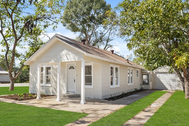 bungalow-style home with a garage, an outdoor structure, and a front lawn